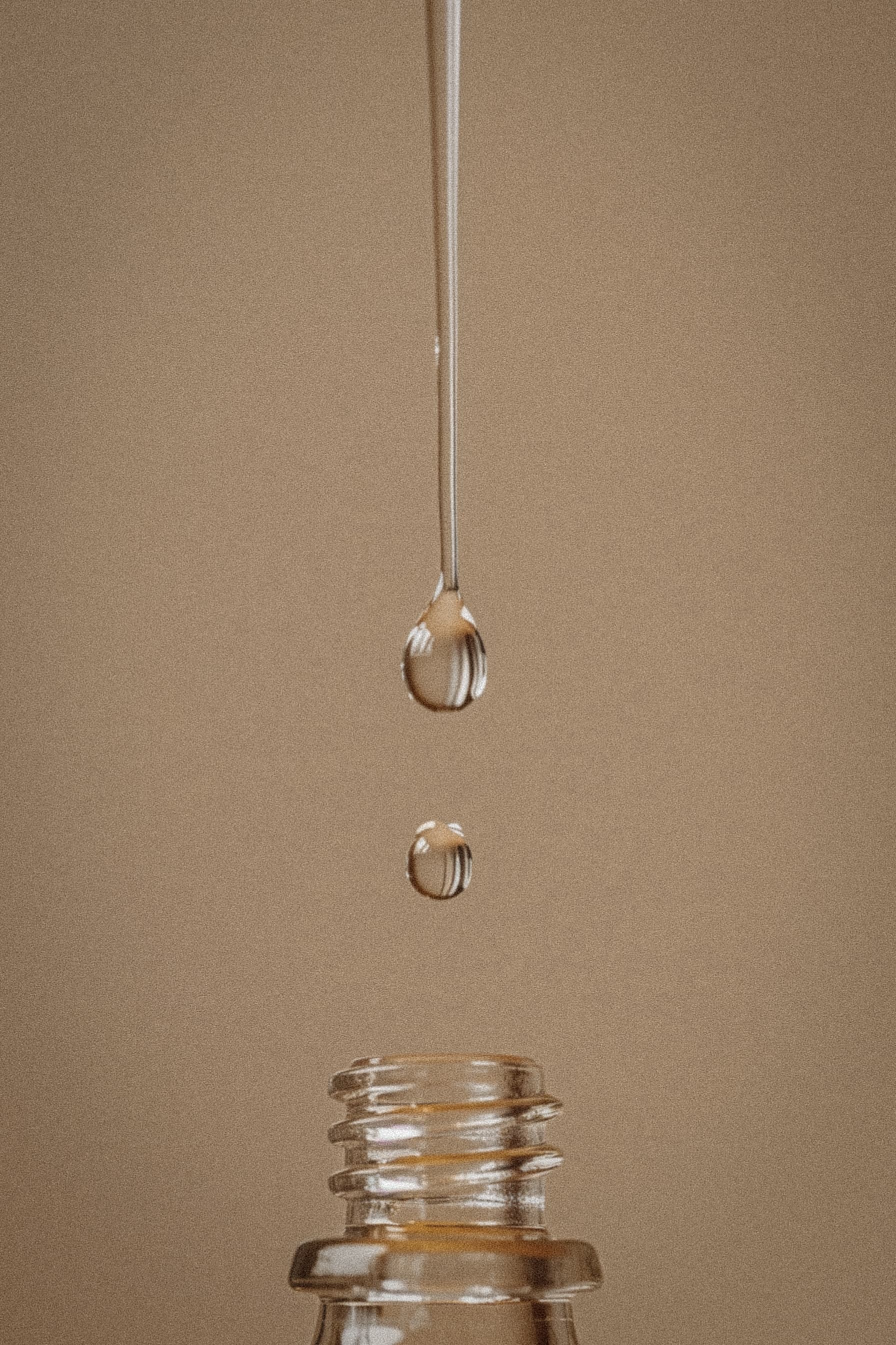 Serum droplet falling into glass bottle representing precision and care